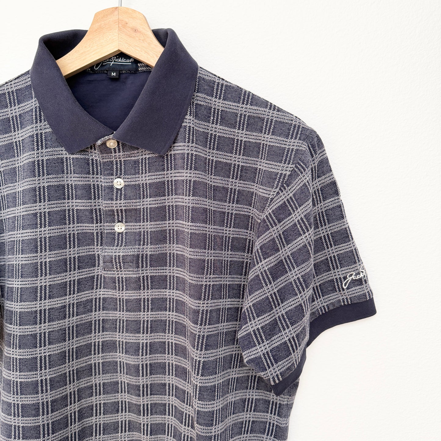 Plaid polo shirt on a hanger with a visible brand logo.