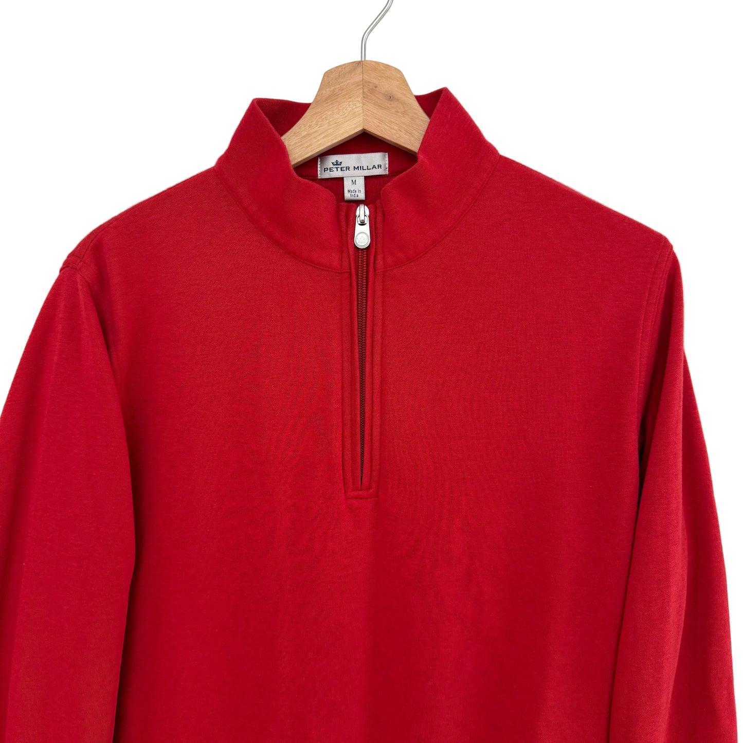 Red long-sleeve shirt with a quarter zip on a wooden hanger against a white background