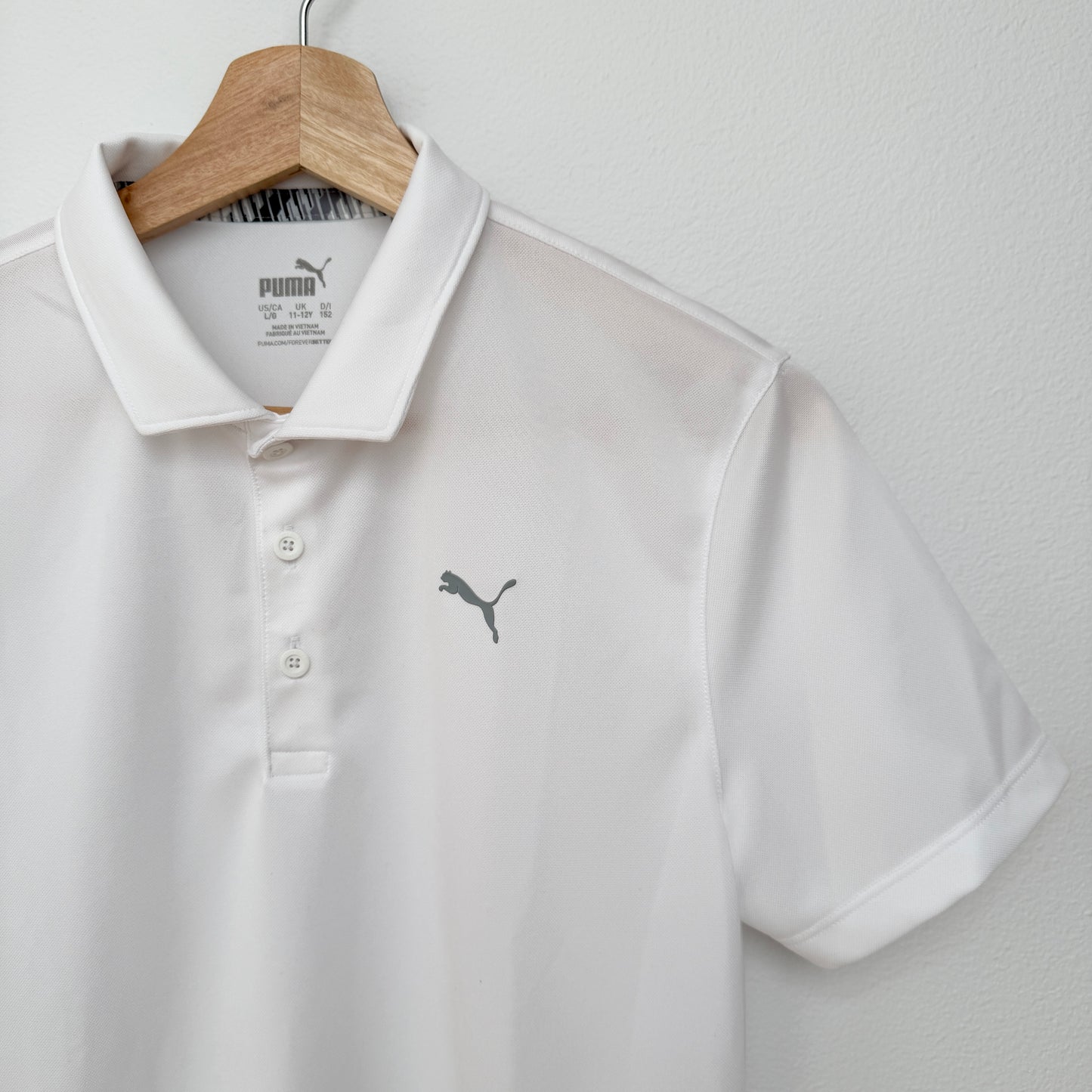 White polo shirt with Puma logo on a hanger against a light gray background