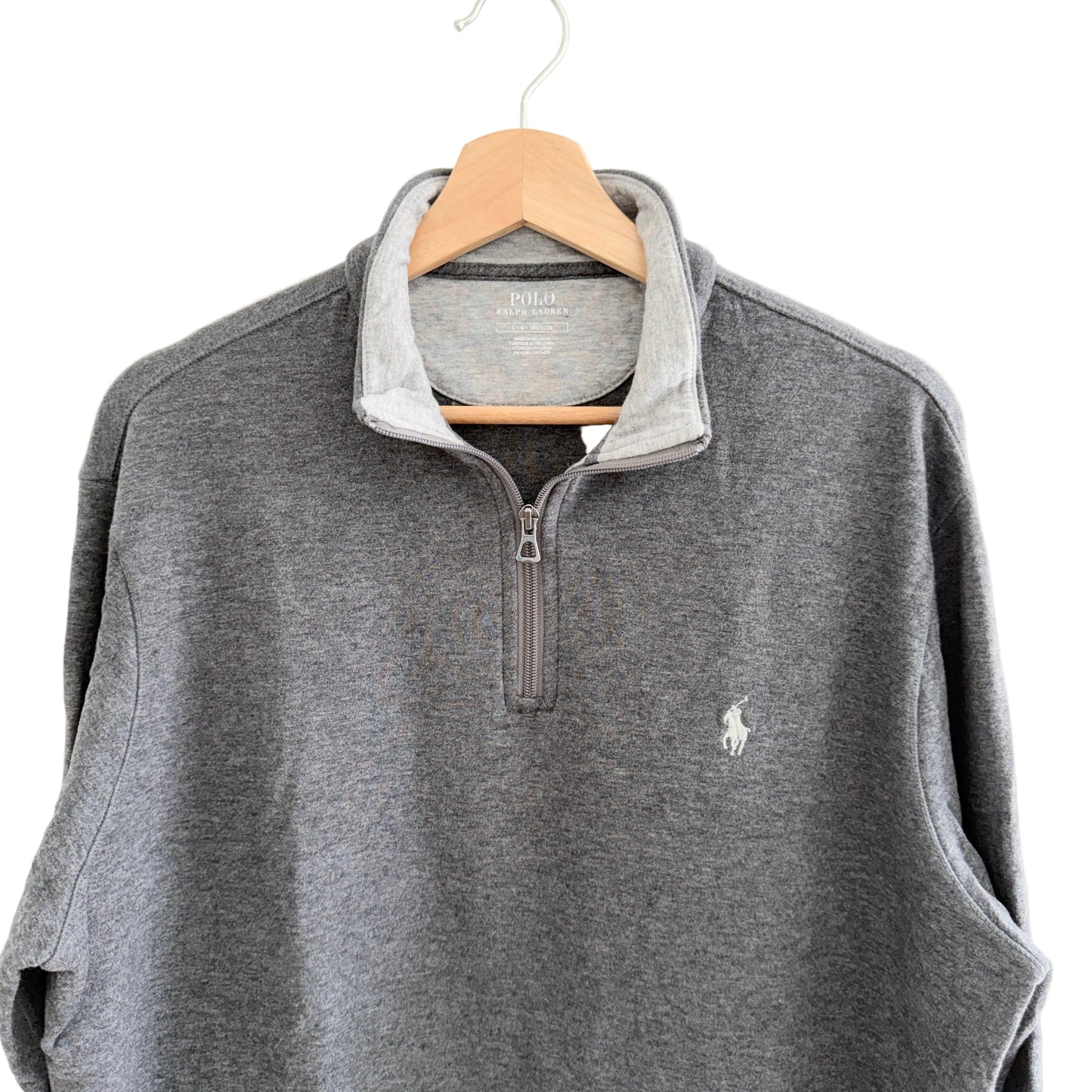 Gray pullover with a small logo on a hanger against a white background