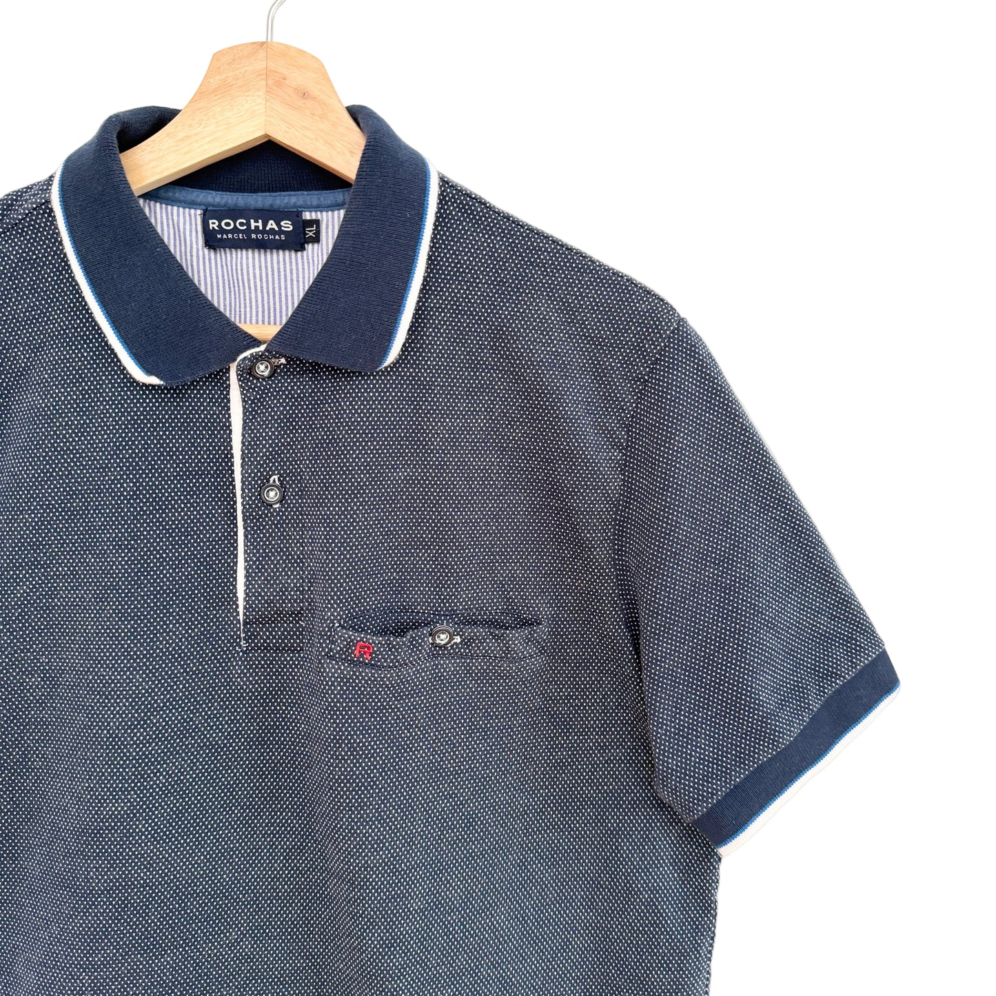 Navy blue polo shirt with white trim on a hanger against a white background