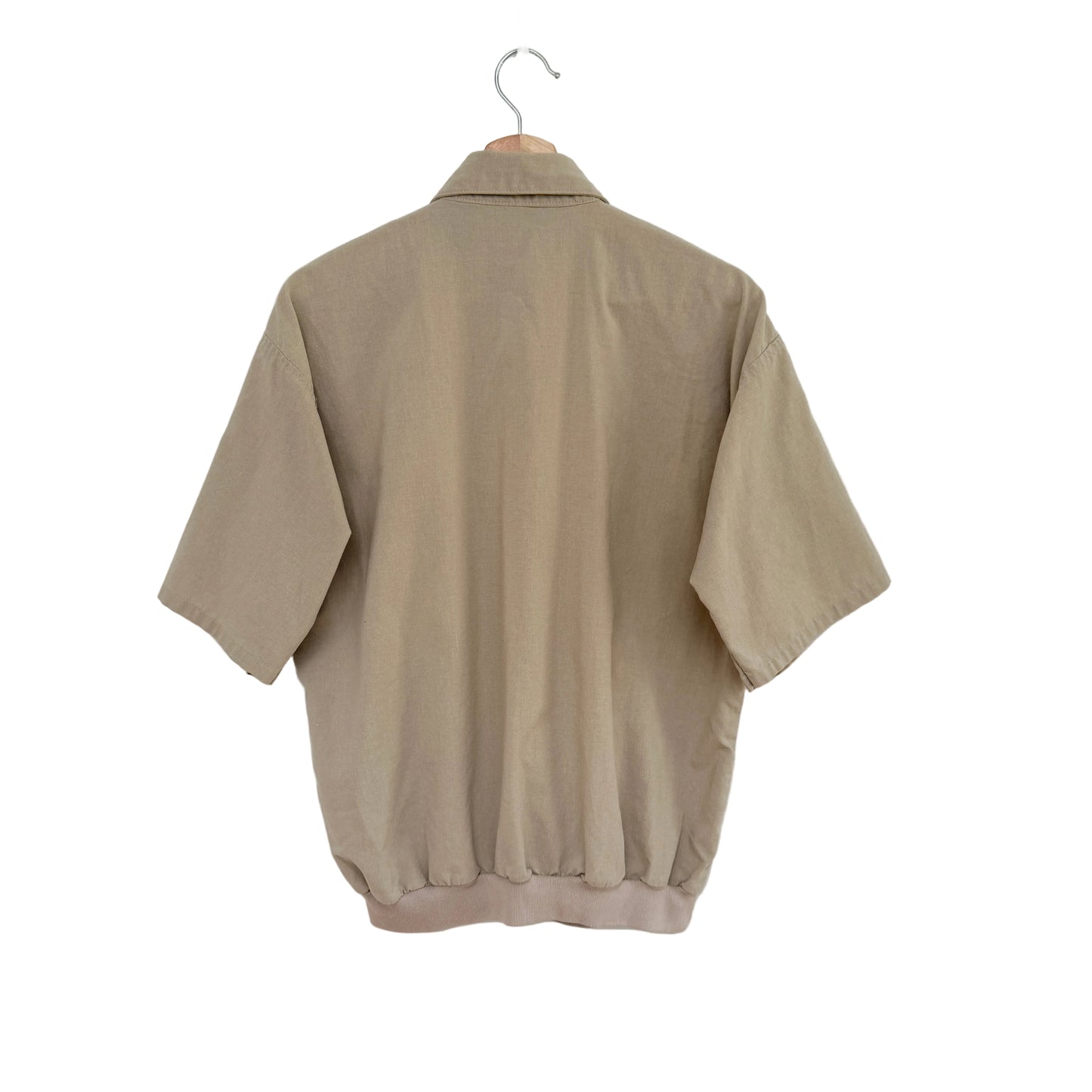 Beige shirt on a hanger against a white background