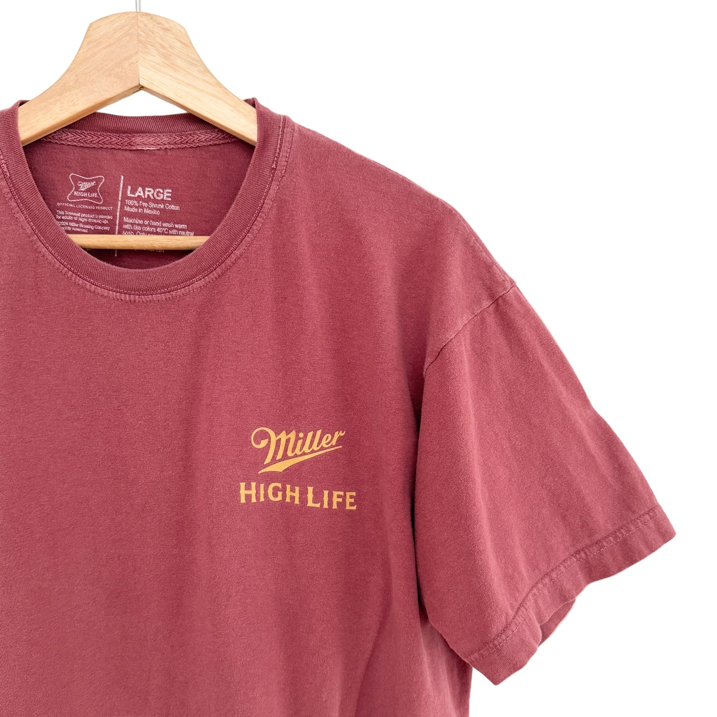 Maroon t-shirt with 'Miller High Life' logo on a hanger against a white background