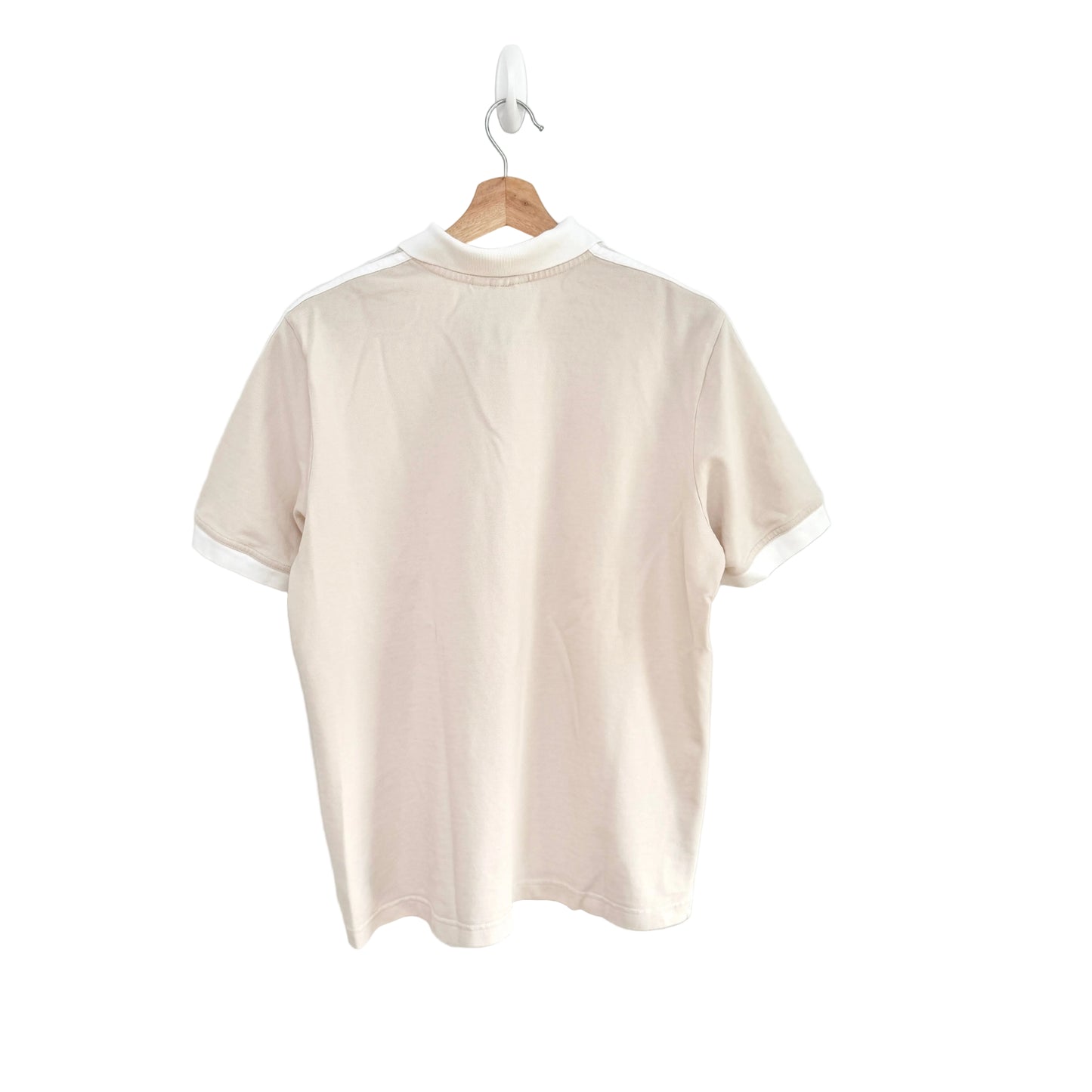 Beige polo shirt on a hanger against a white background