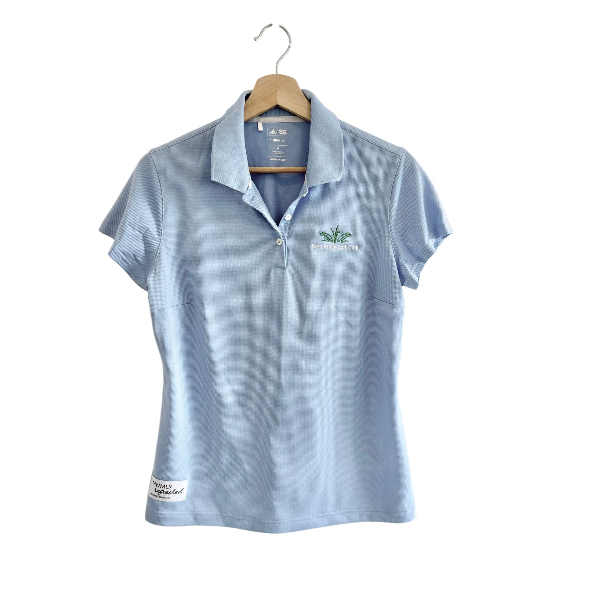 Light blue polo shirt with a logo on a hanger against a white background