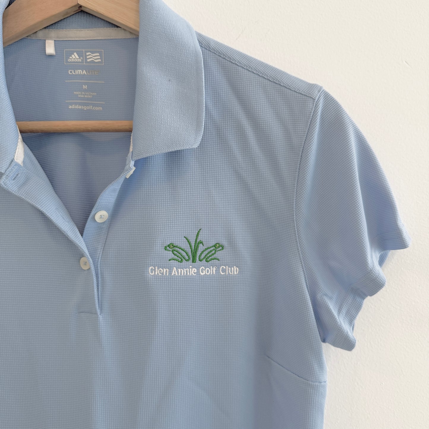 Blue polo shirt with Glen Annie Golf Club logo on a hanger