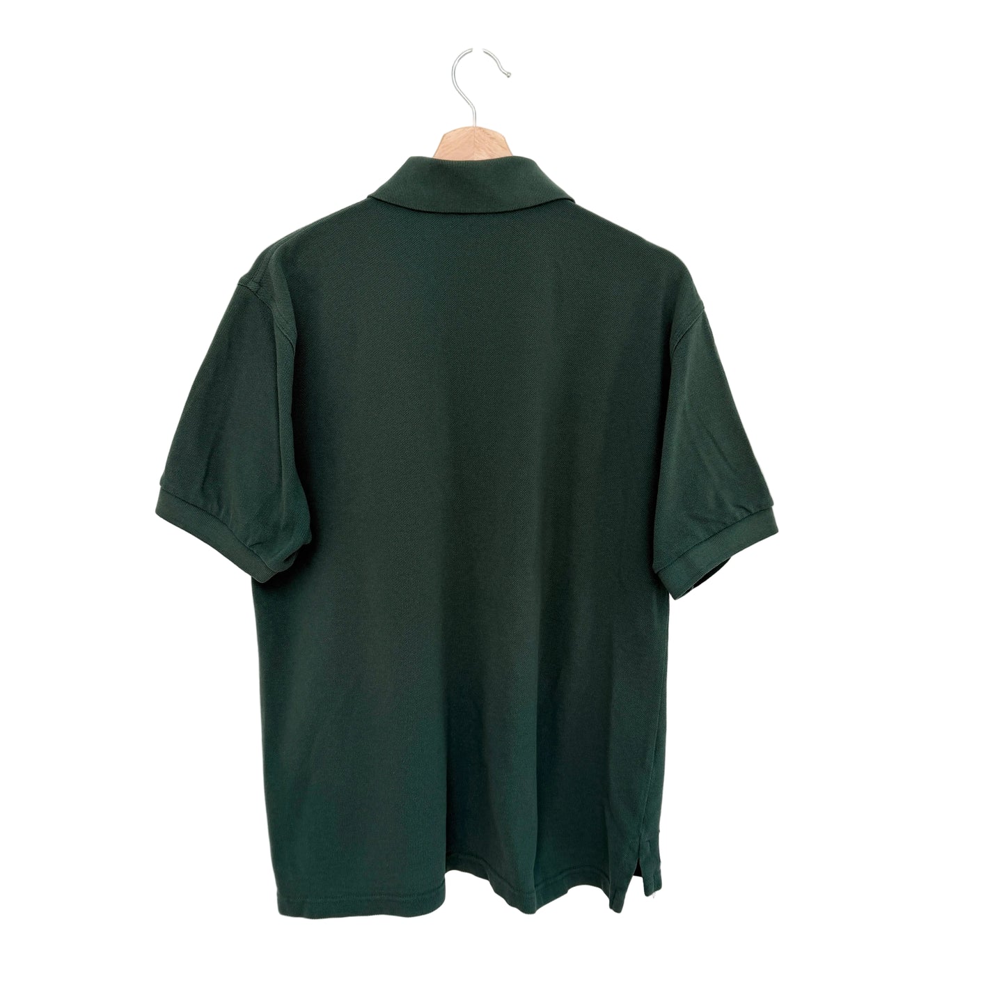 Green polo shirt on a hanger against a white background
