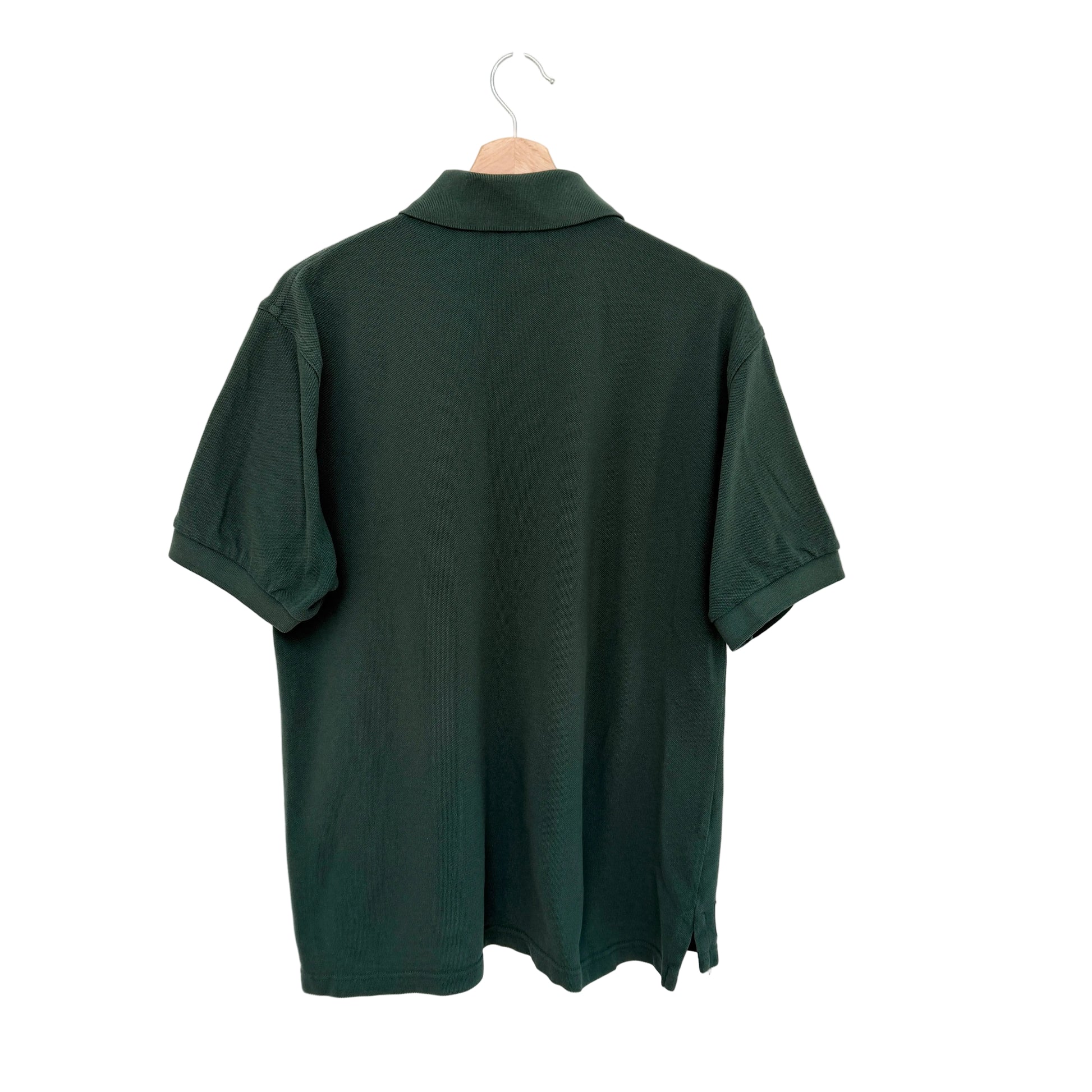 Green polo shirt on a hanger against a white background