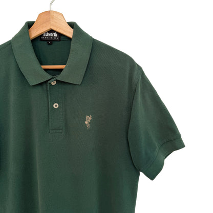 Green polo shirt with a small logo on a hanger against a white background