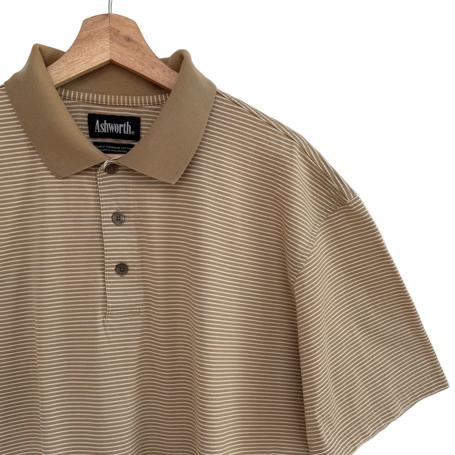 Beige striped polo shirt on a hanger with 'Ashworth' label against a white background