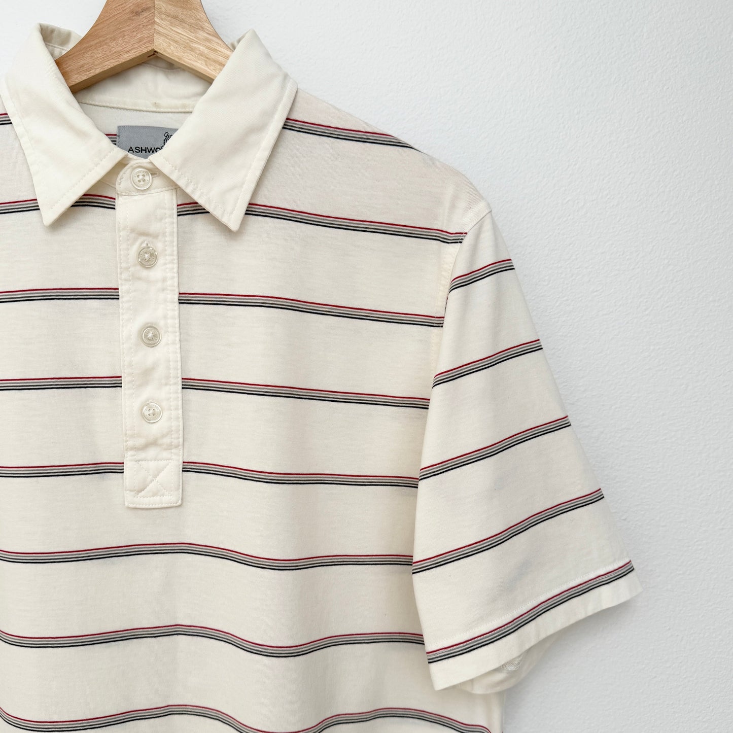 Striped polo shirt on a hanger against a white background