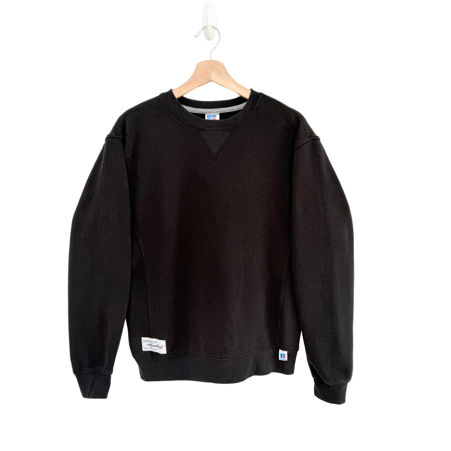 Black sweatshirt on a hanger against a white background