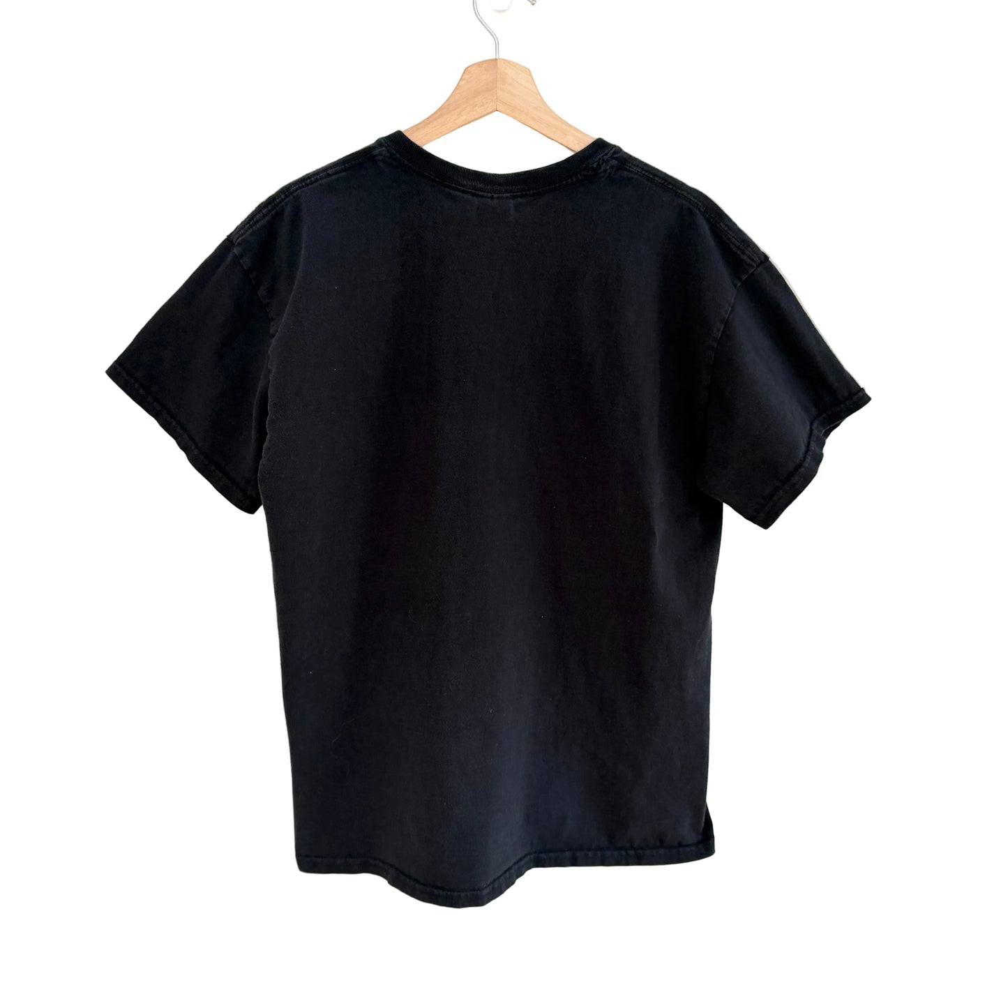 Black t-shirt on a wooden hanger against a white background