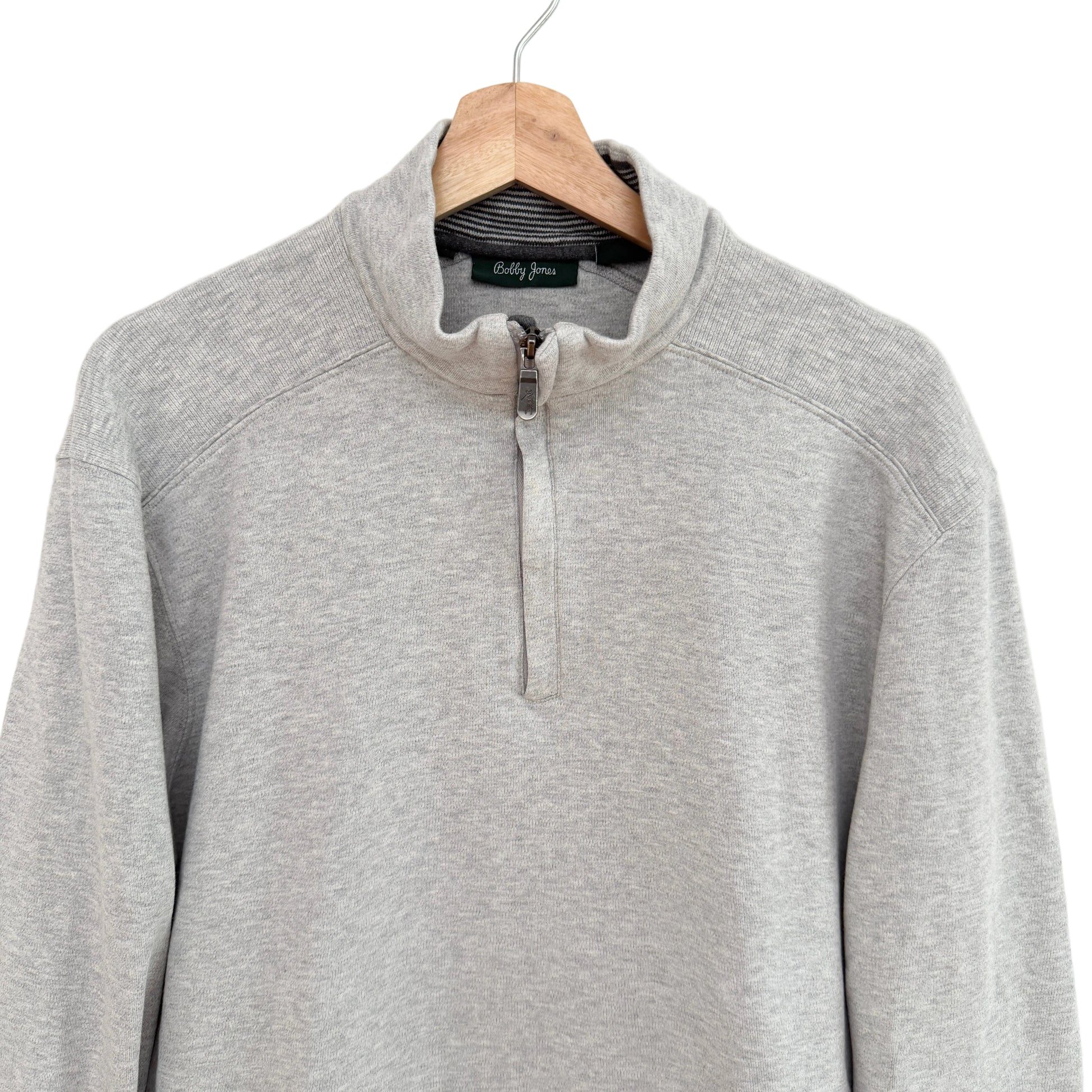 Gray pullover with a quarter zip on a hanger against a white background