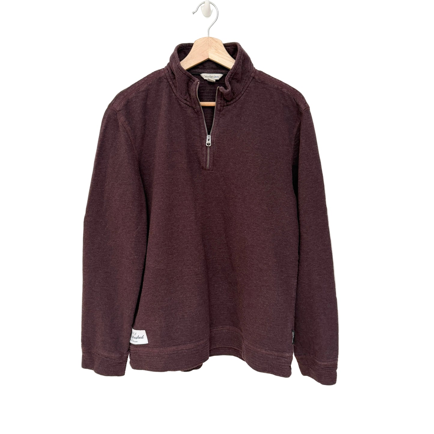 Burgundy pullover on a hanger against a white background