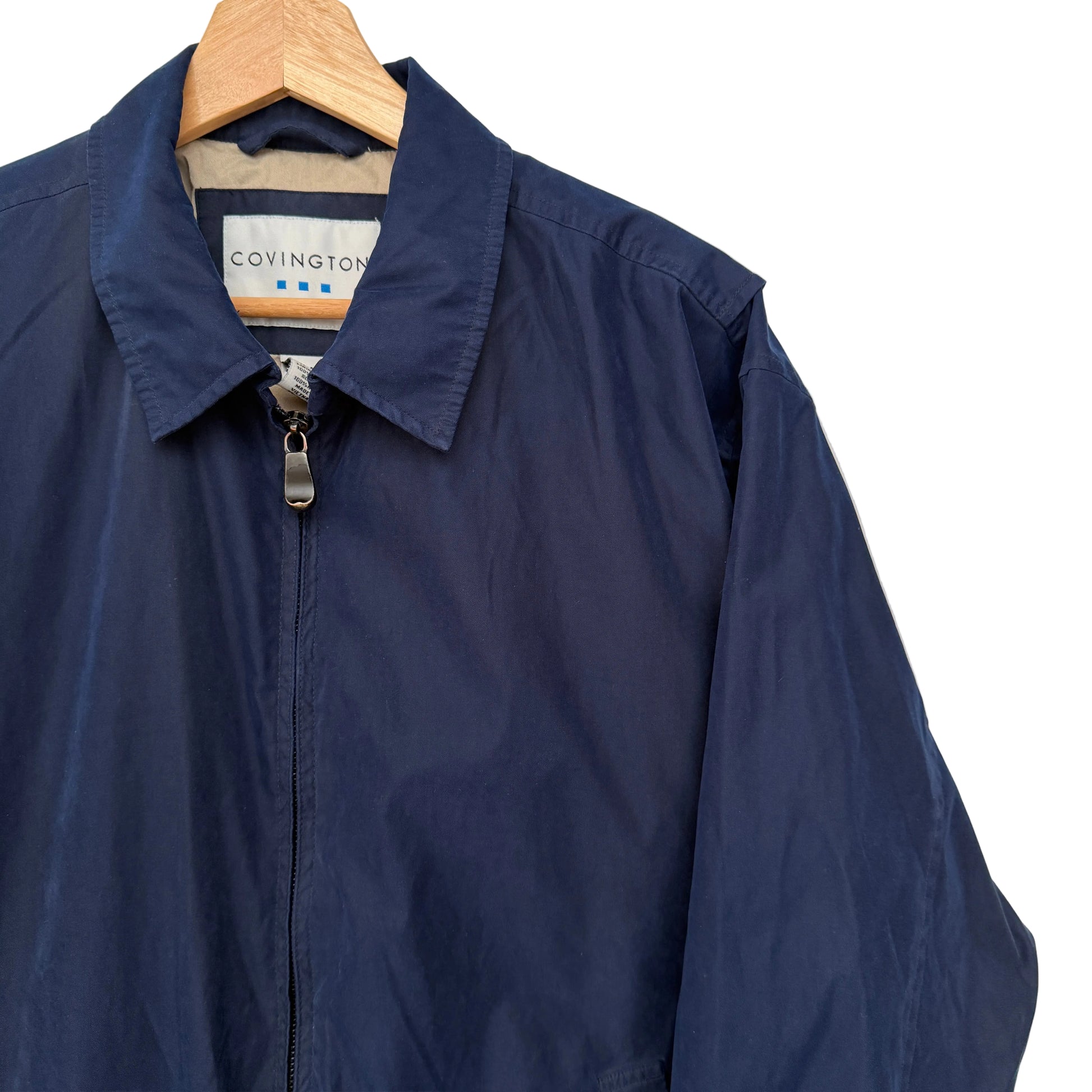 Navy blue jacket on a hanger with a visible brand label against a plain background