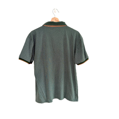 Green polo shirt on a hanger against a white background