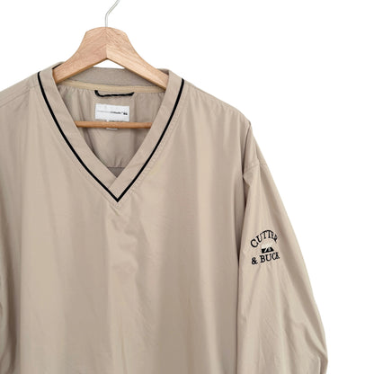Beige shirt with black trim and 'Cutter & Buck' logo on a hanger against a white background