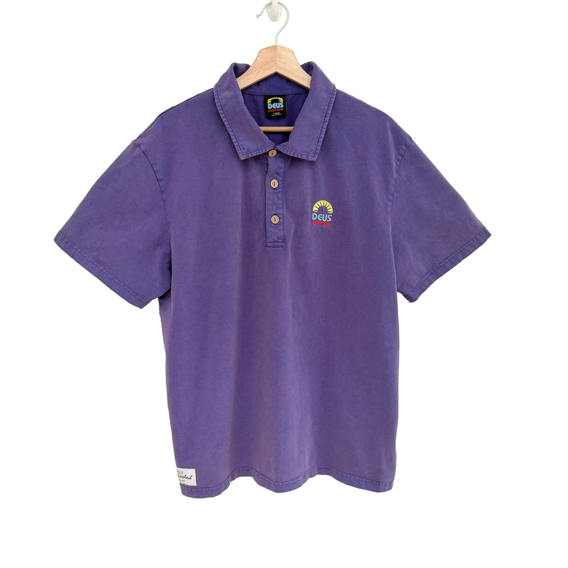 Purple polo shirt with a logo on a hanger against a white background