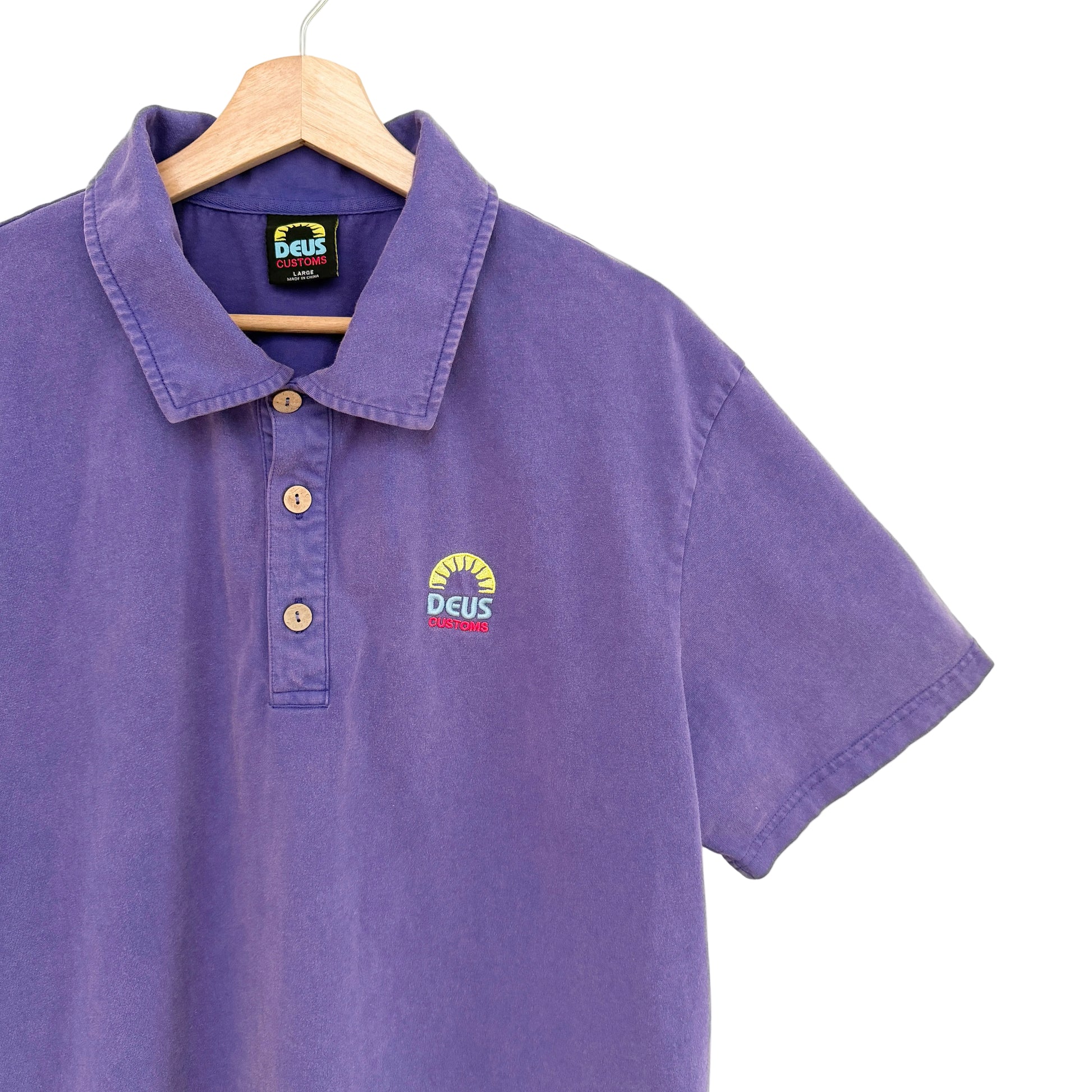 Purple polo shirt with a logo on a hanger against a white background