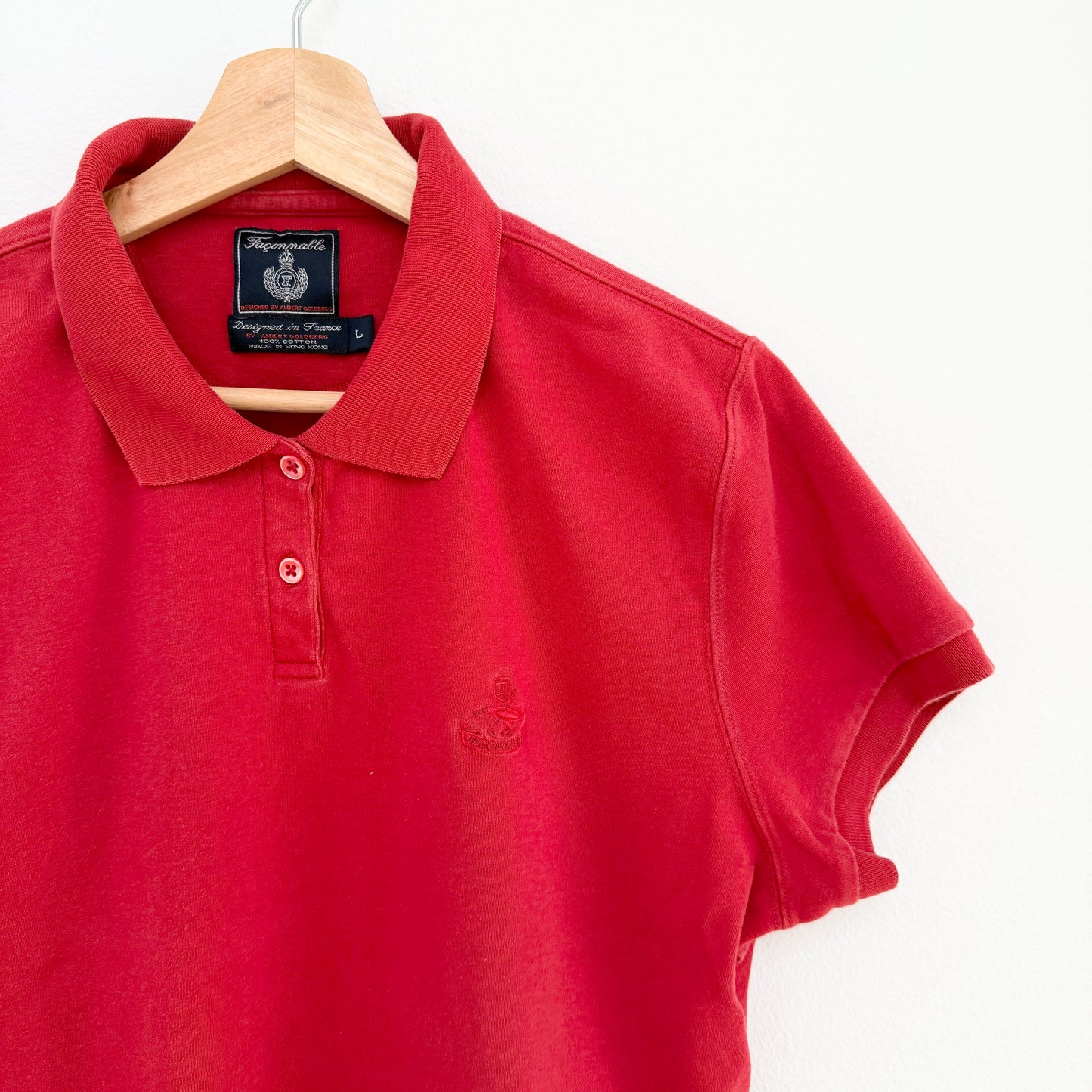 Red polo shirt on a hanger with a visible brand label against a white background