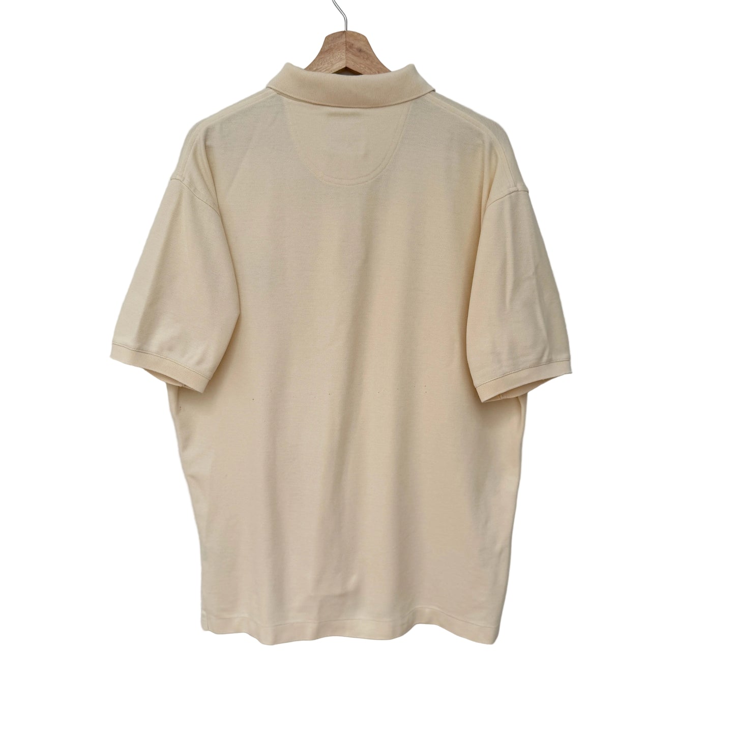 Beige polo shirt on a hanger against a light gray background