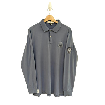 Slate blue long-sleeve polo shirt with logos on a beige background