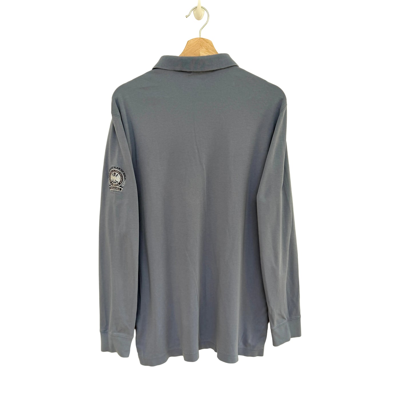 Slate blue long-sleeve polo shirt on a hanger against a beige background