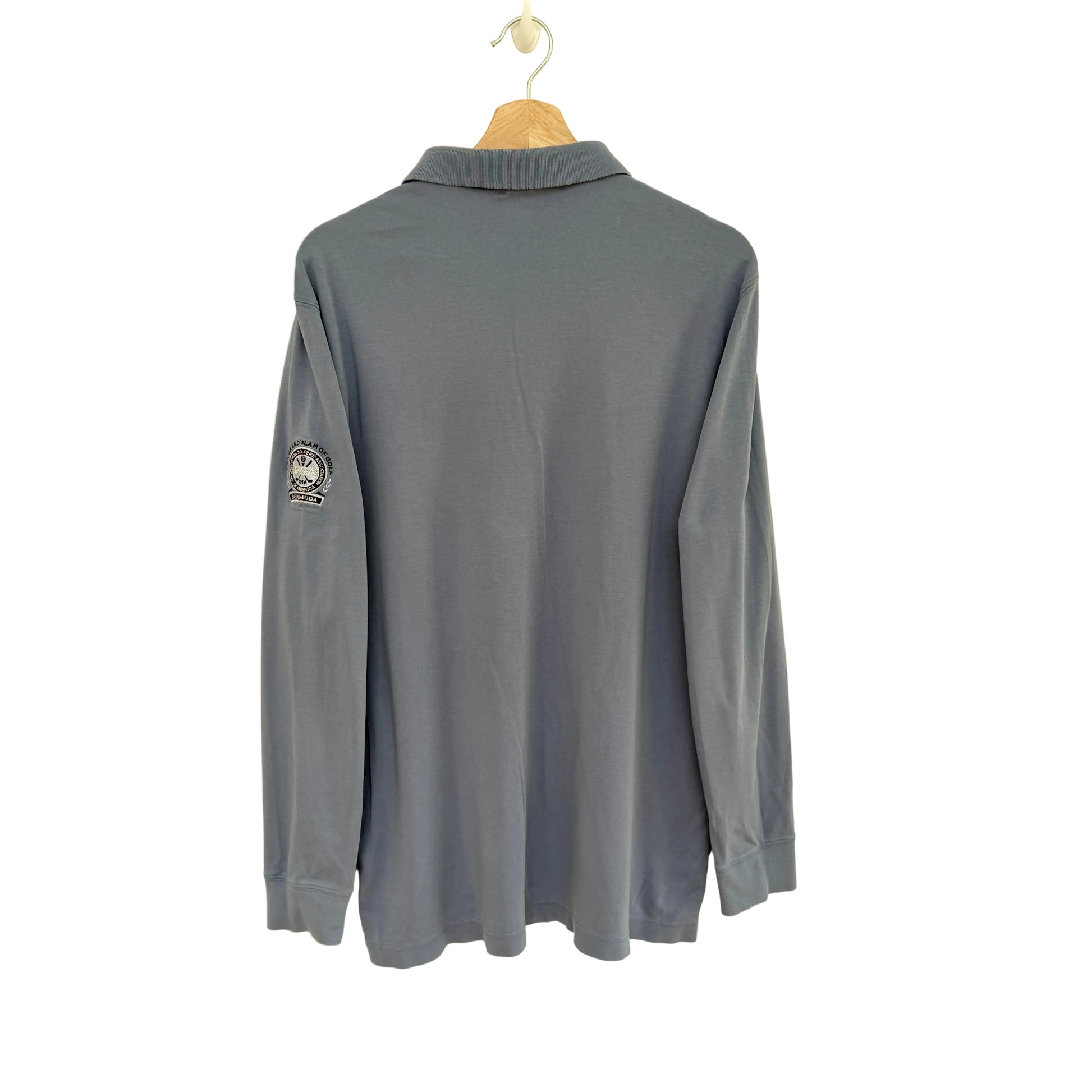 Slate blue long-sleeve polo shirt on a hanger against a beige background