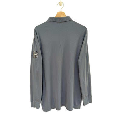 Slate blue long-sleeve polo shirt on a hanger against a beige background