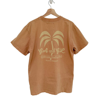 Peach t-shirt with palm tree design and text on a hanger against a white background
