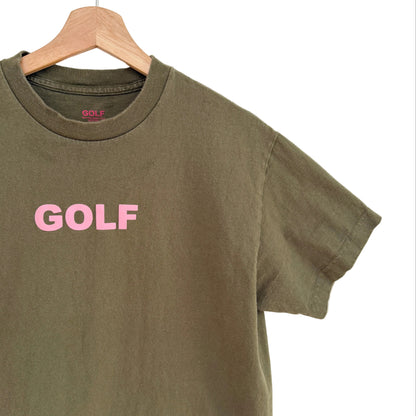Green t-shirt with 'GOLF' printed in pink on a wooden hanger against a white background