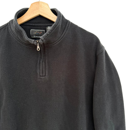 Black cotton pullover on a wooden hanger against a beige background