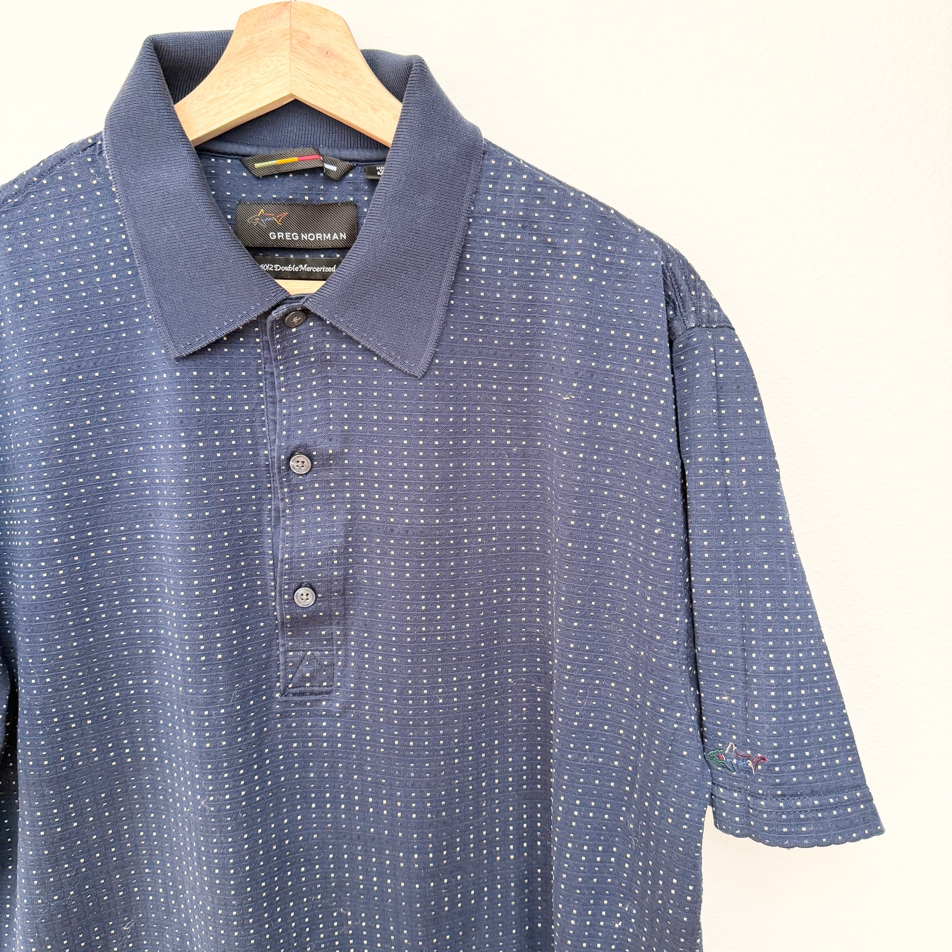 Blue patterned polo shirt on a hanger with a white background