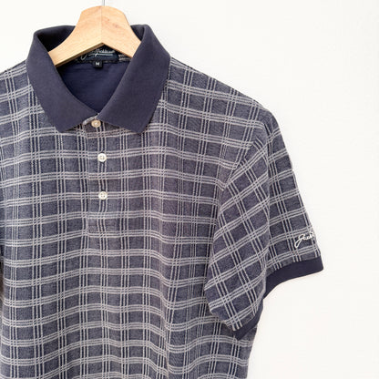 Plaid polo shirt on a hanger with a visible brand logo.