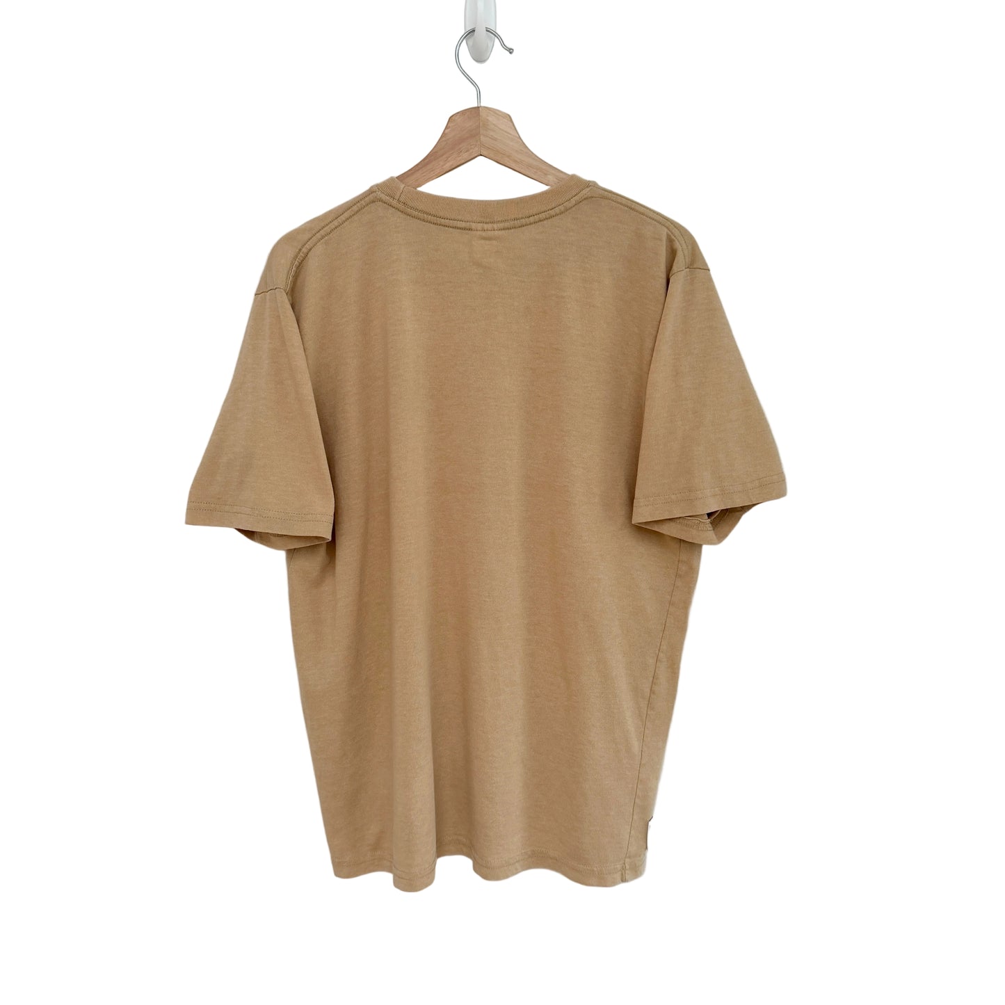 Beige t-shirt on a hanger against a white background
