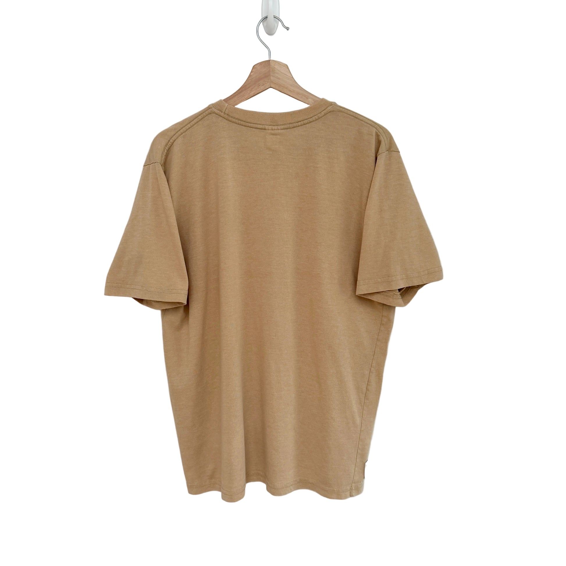 Beige t-shirt on a hanger against a white background