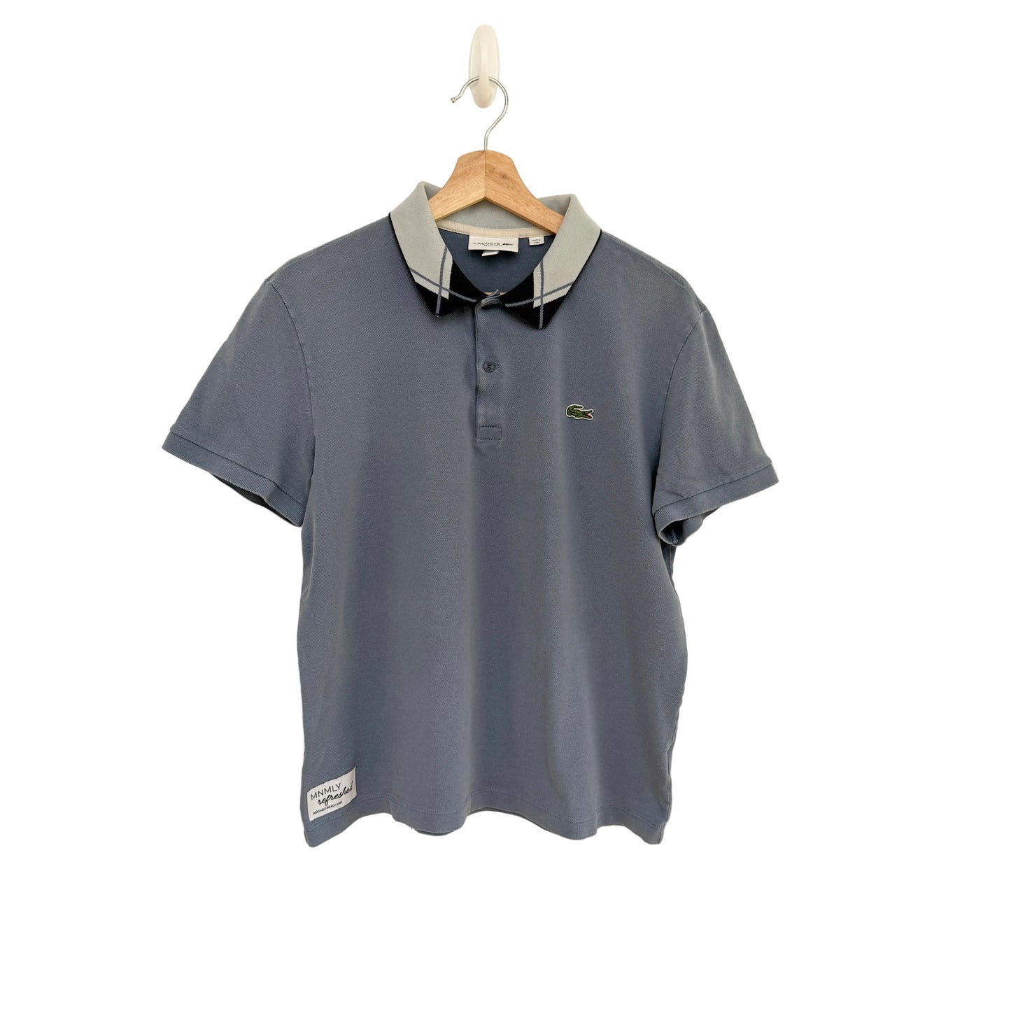 Blue polo shirt on a hanger against a beige background