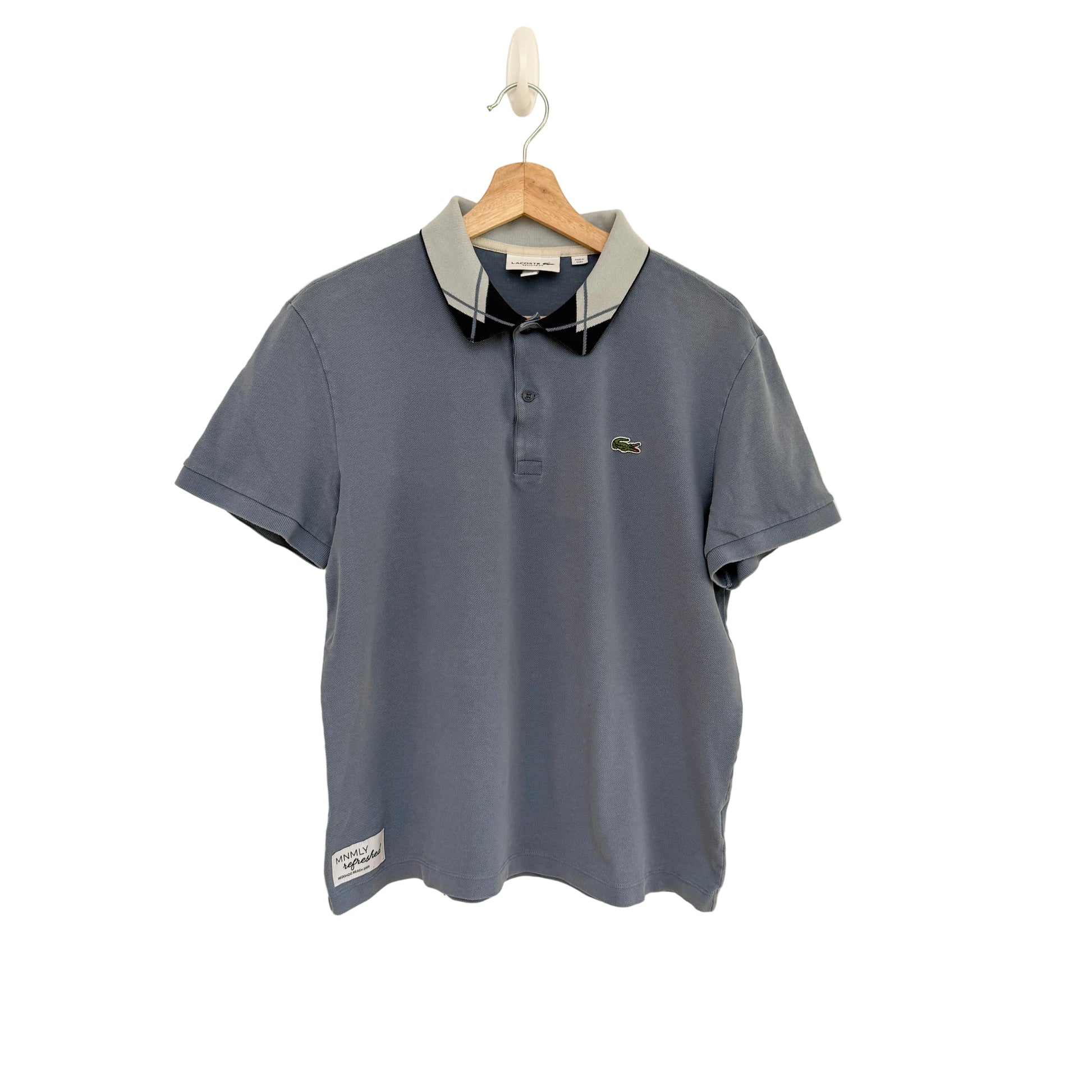 Blue polo shirt on a hanger against a beige background