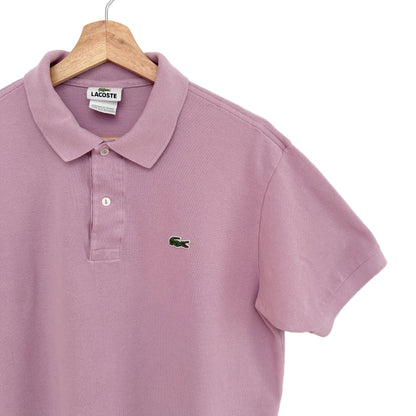 Purple polo shirt with Lacoste logo on a wooden hanger against a white background