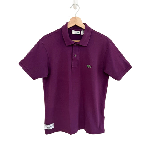 Purple polo shirt on a hanger against a white background