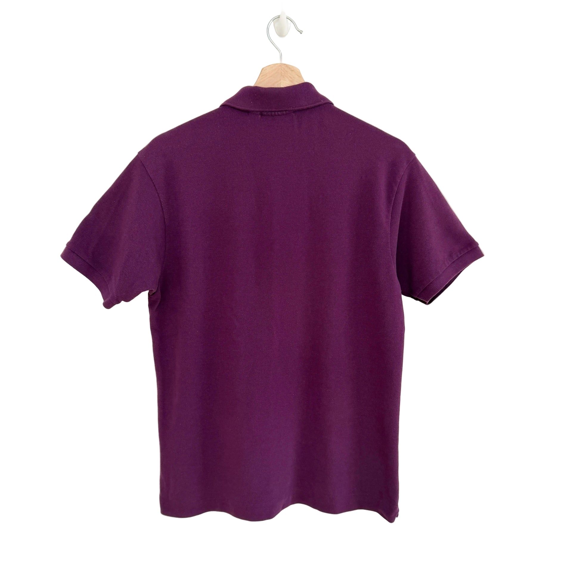 Purple polo shirt on a hanger against a white background