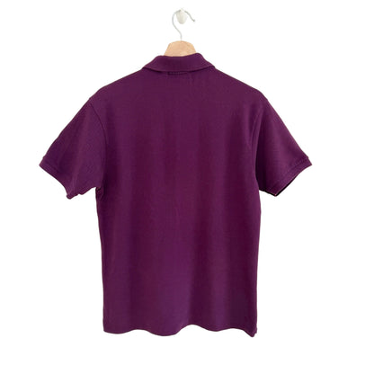 Purple polo shirt on a hanger against a white background