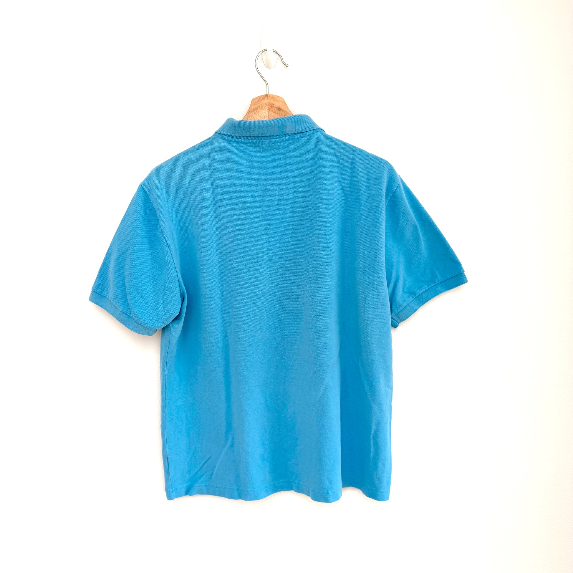 Blue polo shirt on a hanger against a white background