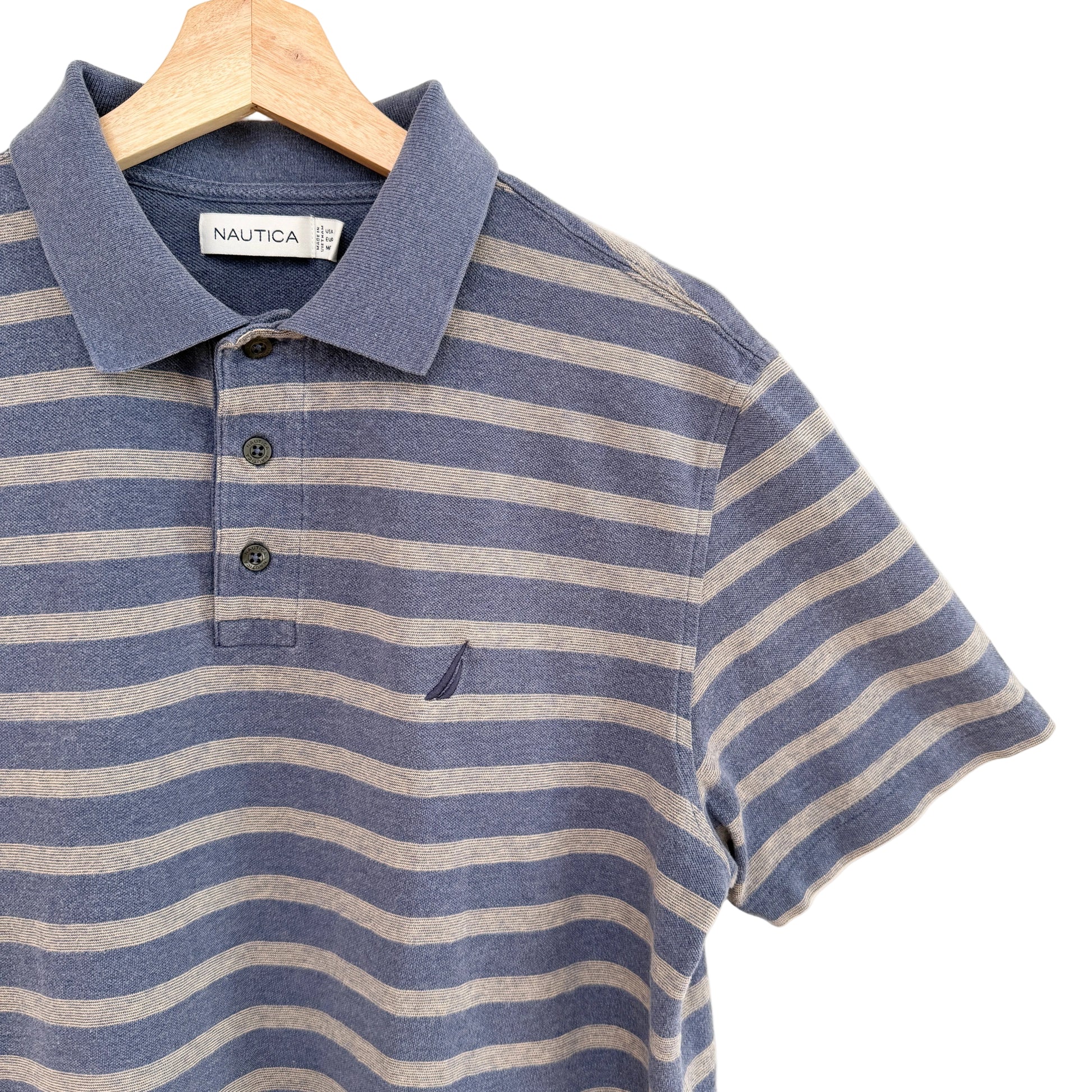 Blue and beige striped polo shirt on a hanger with Nautica label.
