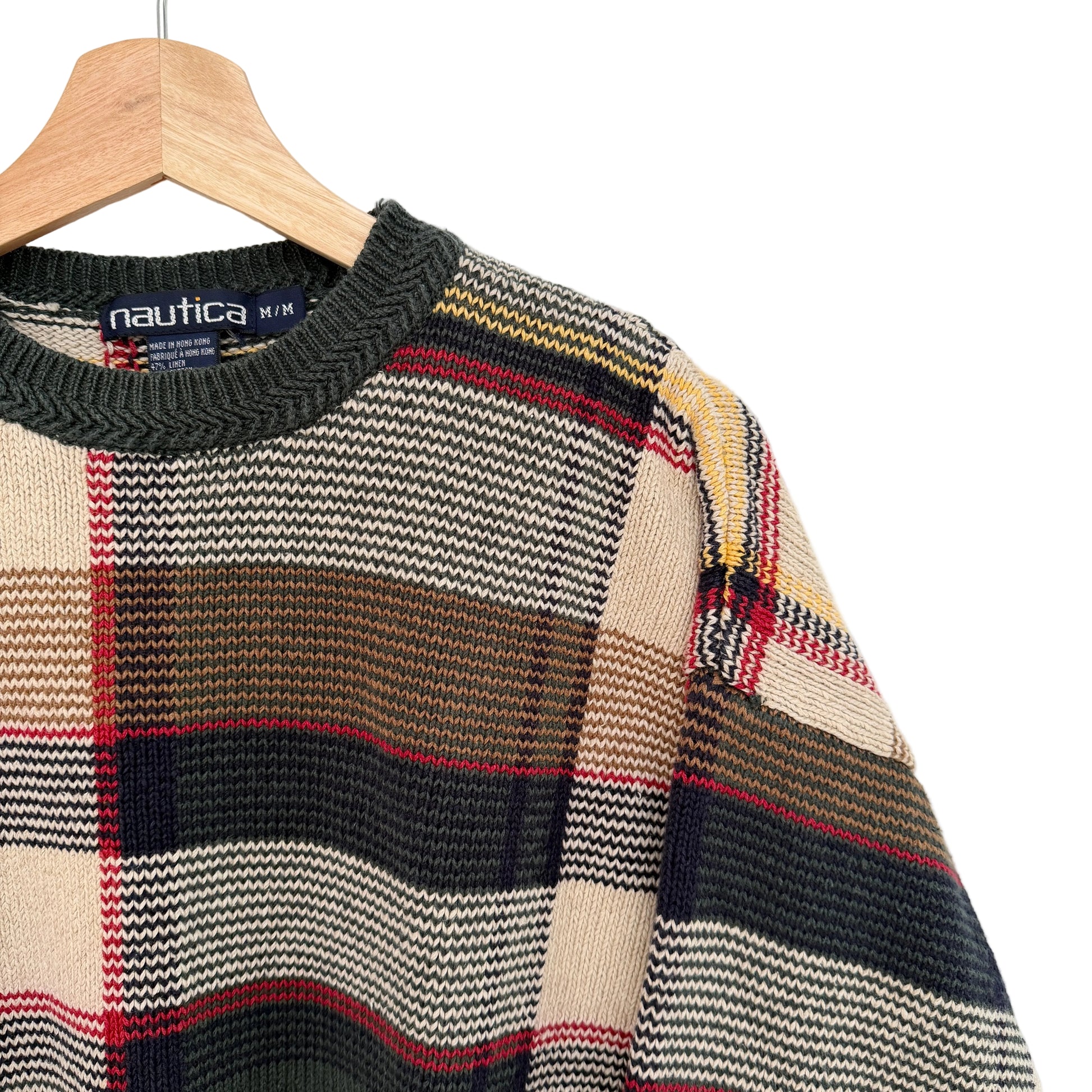 Plaid sweater with Nautica label on a hanger against a white background