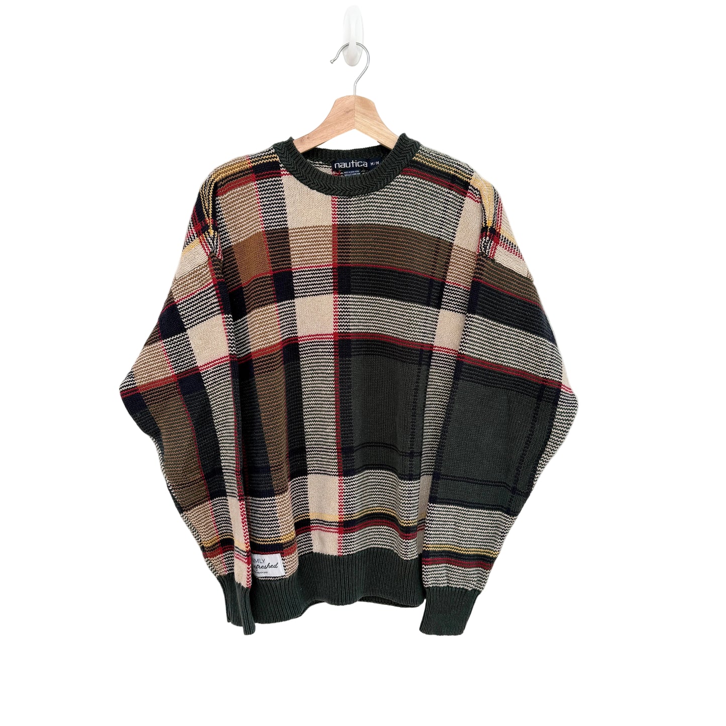 Plaid sweater on a hanger against a white background