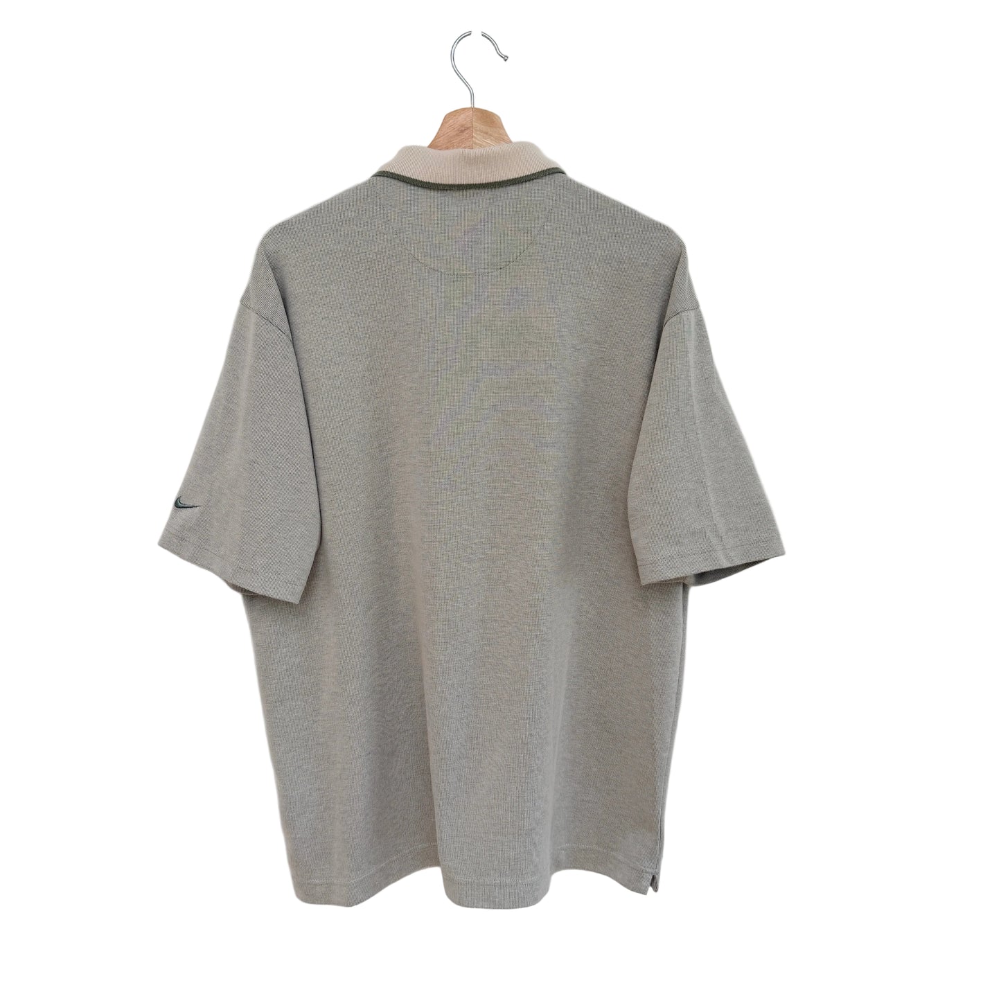 Green golf shirt on a hanger against a white background