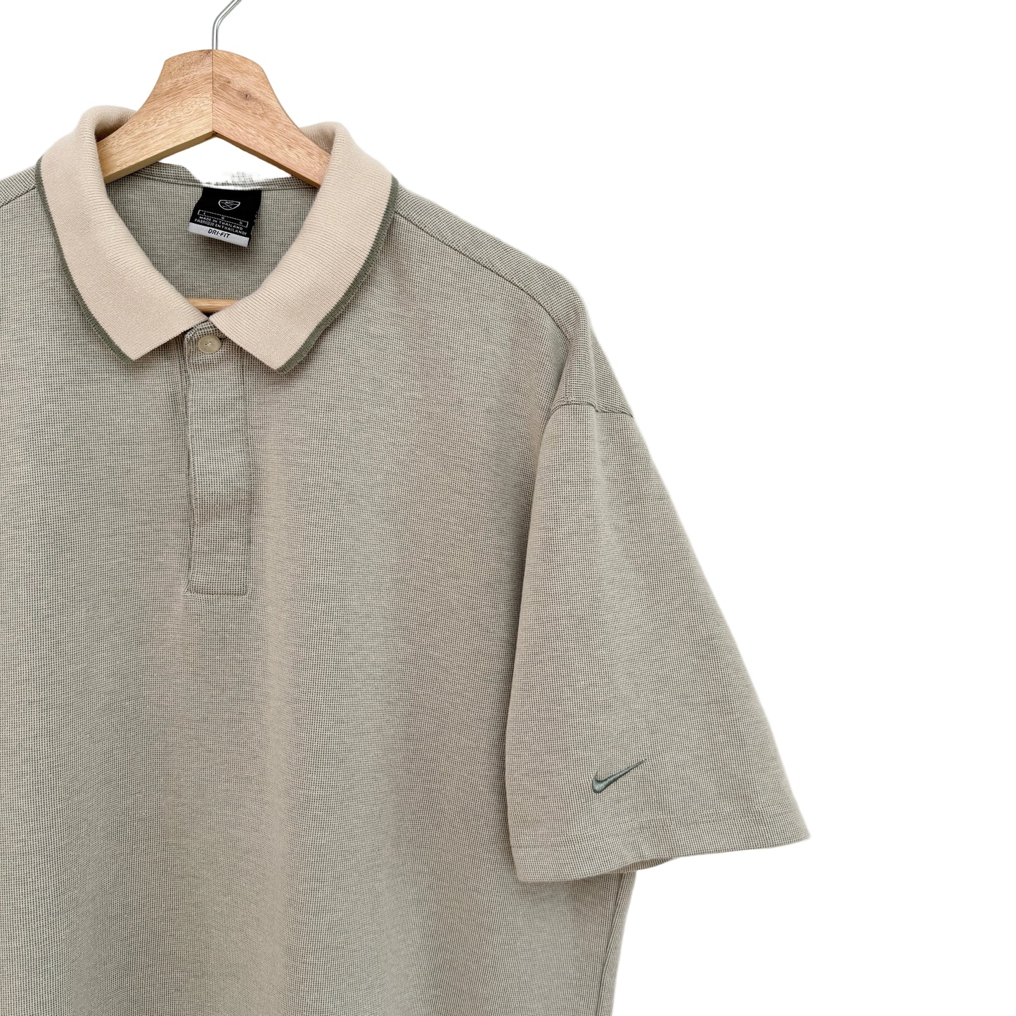 Green polo shirt with beige collar on a wooden hanger against a white background