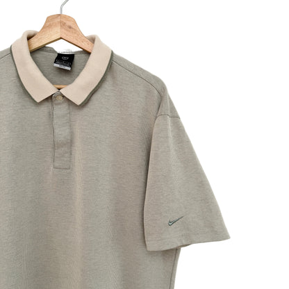Green polo shirt with beige collar on a wooden hanger against a white background